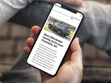 A car shopper searching for affordable SUVs on a phone, viewing a Carolina dealer's listing