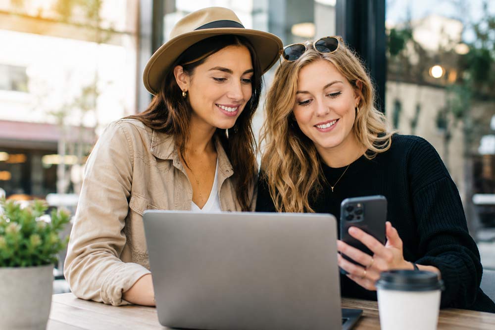 Two women looking at a phone, researching dealerships online